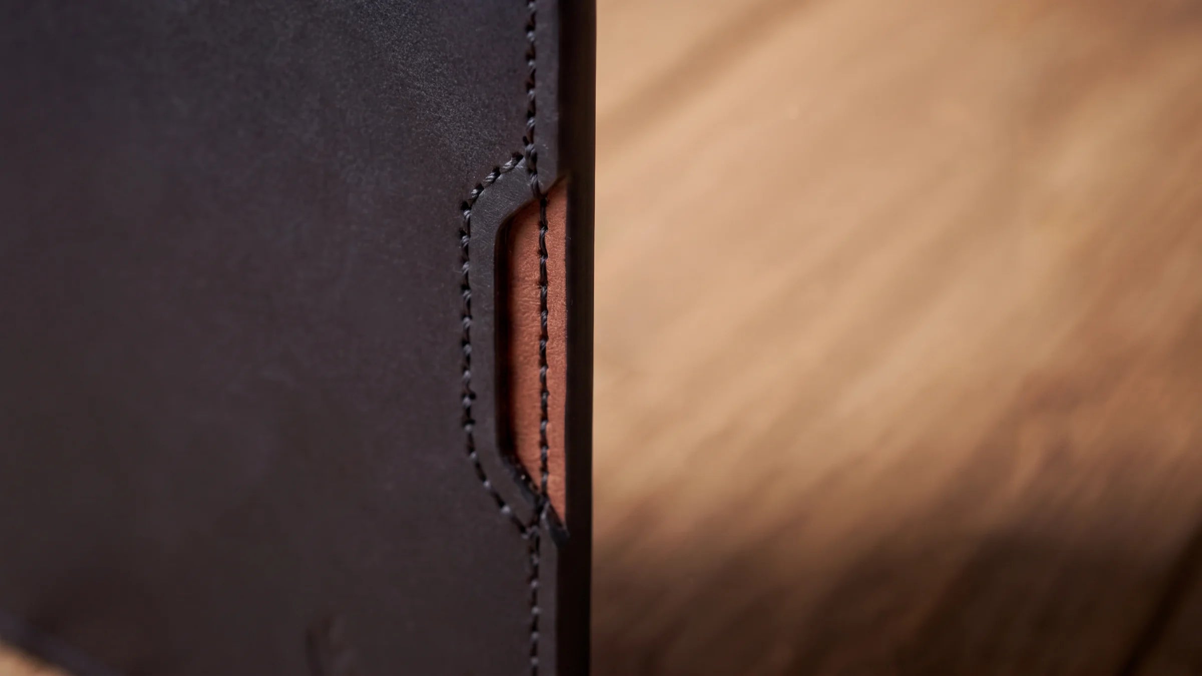 Close view of the black exterior and walnut interior layers of the OB-01 wallet