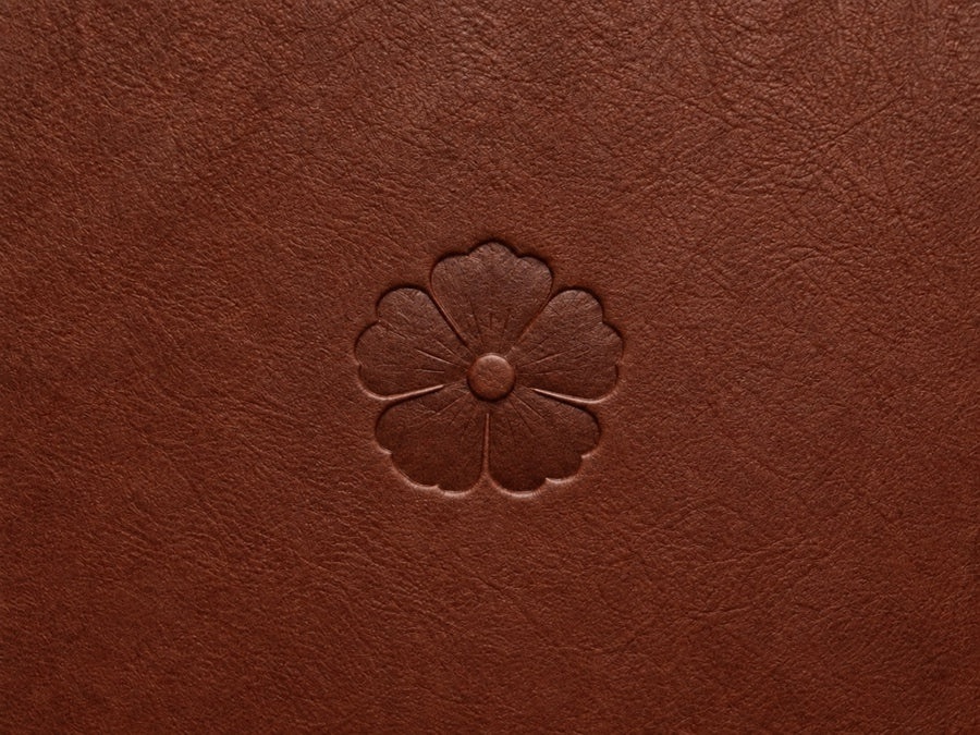 Close-up of the centered amapola Heritage Seal embossed in walnut leather