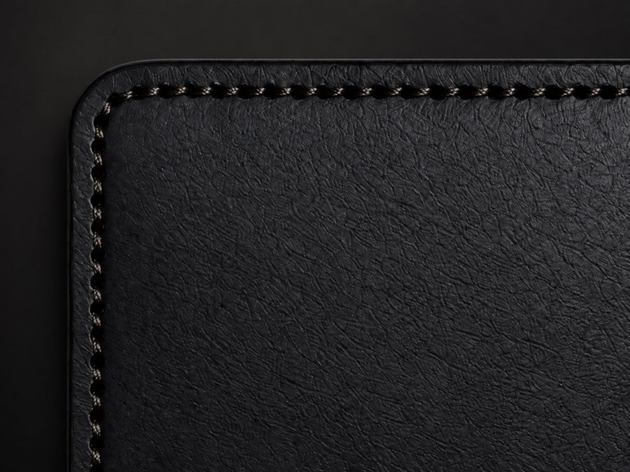 Close view of hand saddle stitching along a black leather wallet edge